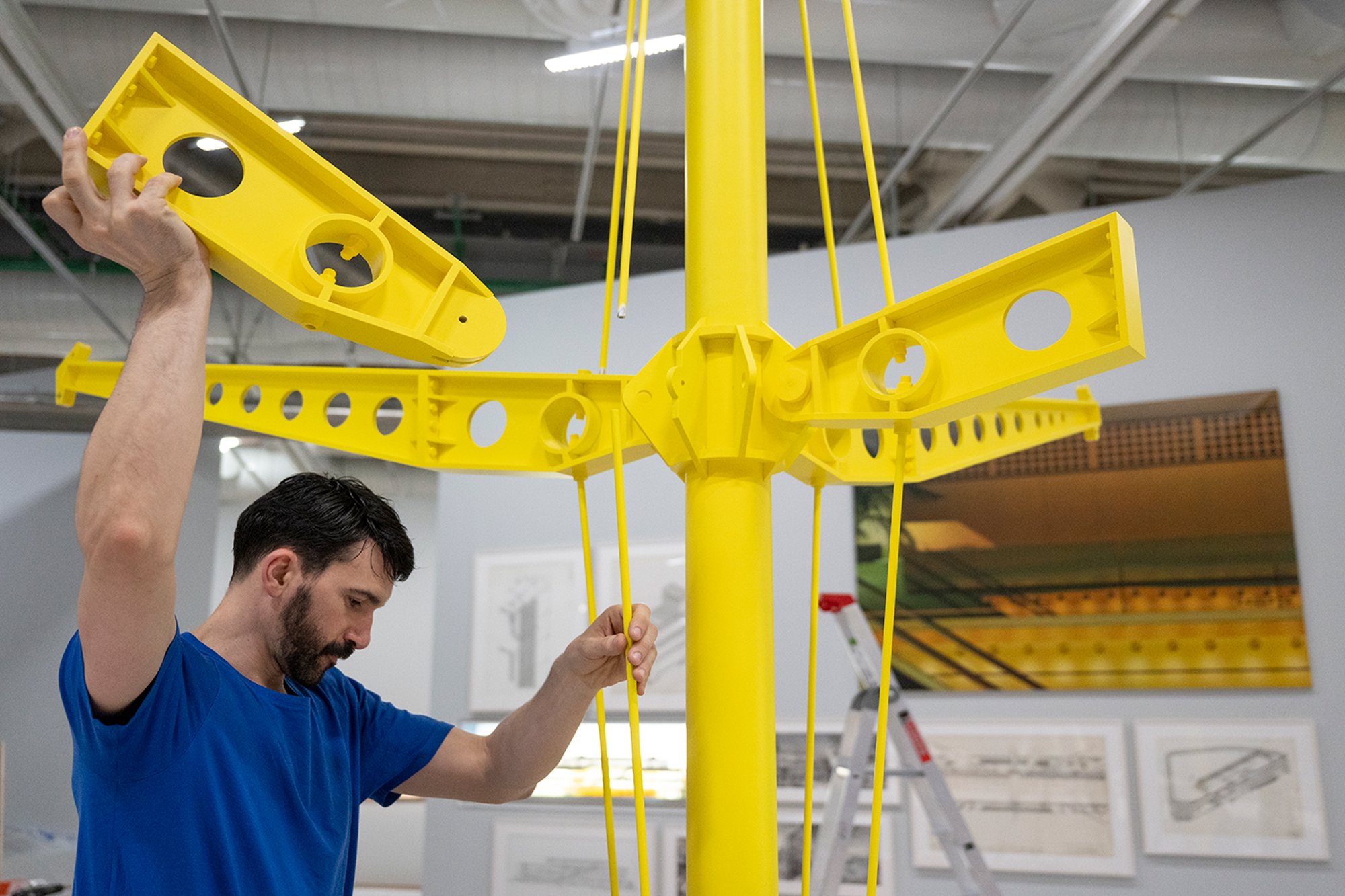 Reassembling the model of the Renault Distribution Centre's yellow skeleton. The centre has been described as the practice's most playful structure. However, its development owes much to earlier schemes for clients such as Reliance Controls and Fred Olsen, which delivered inexpensive, flexible buildings to tight schedules.